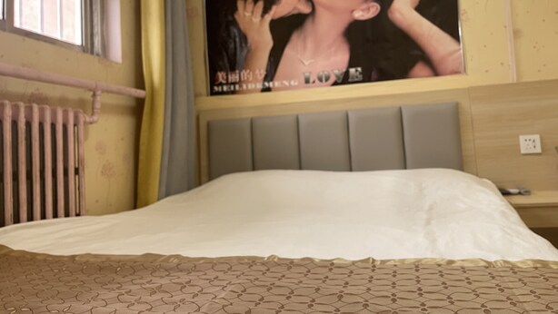 A hotel room with a bed, a radiator, a poster on the wall, and a window with curtains. - Beijing Huairou Pan Jia Yuan Hotel (Huairou)