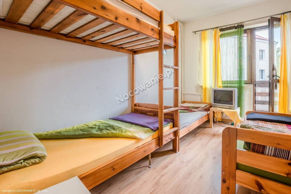 Une chambre de dortoir avec des lits superposés, une petite télévision et une fenêtre avec des rideaux.