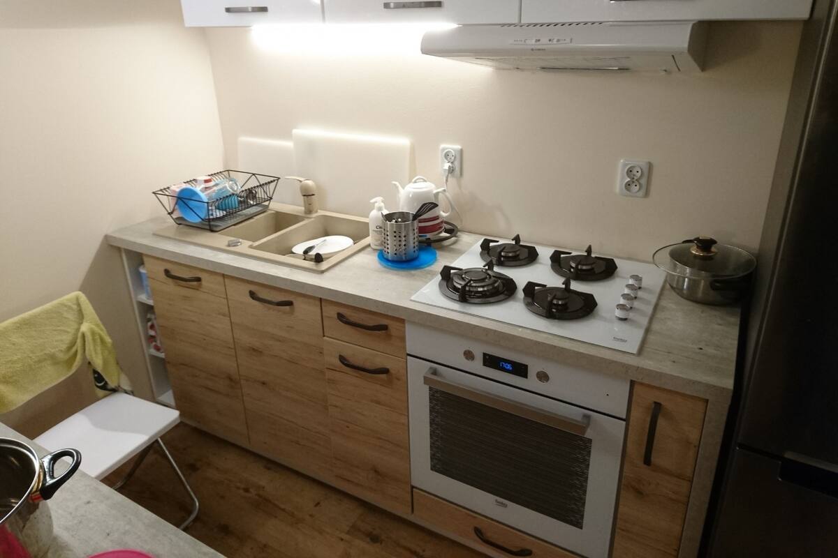 Une cuisine équipée d’une cuisinière à gaz, d’un four, d’un évier et de meubles de rangement en bois.