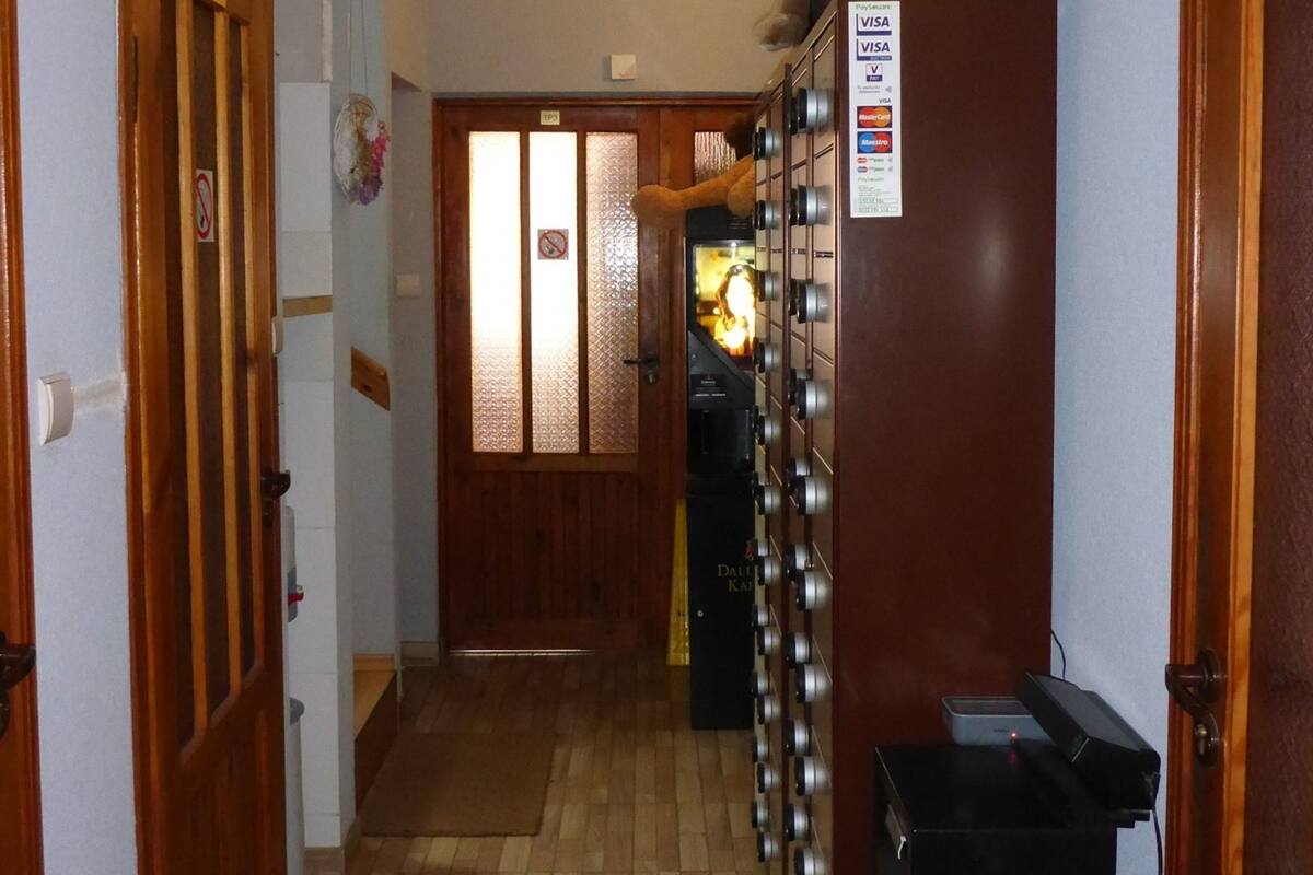 Un couloir avec des portes en bois, une horloge, un distributeur automatique et une caméra de surveillance.
