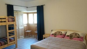 A bedroom with a bunk bed, a single bed with two dogs, a chair, a desk, and a window with curtains. - Agriturismo da Ysy (Civo)