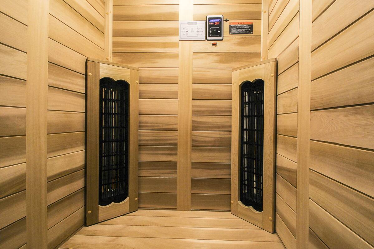 A sauna room with wooden walls and two black doors.