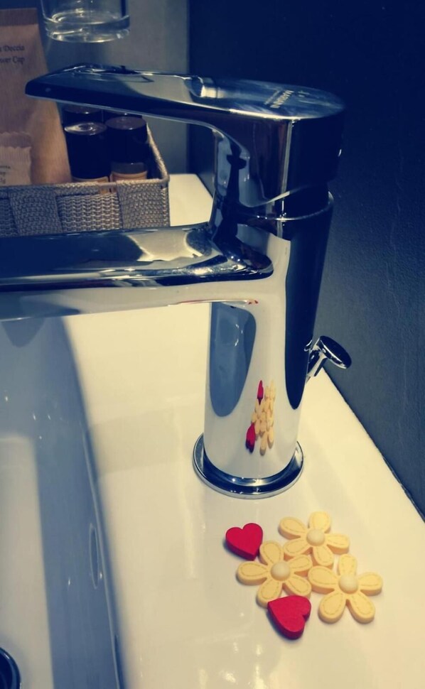 A bathroom sink with a chrome faucet and a decorative vase with hearts and flowers.