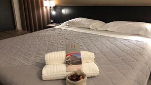 Una habitación de hotel con una cama bien hecha, una mesita de noche con lámpara y una pared decorada con elementos rústicos.