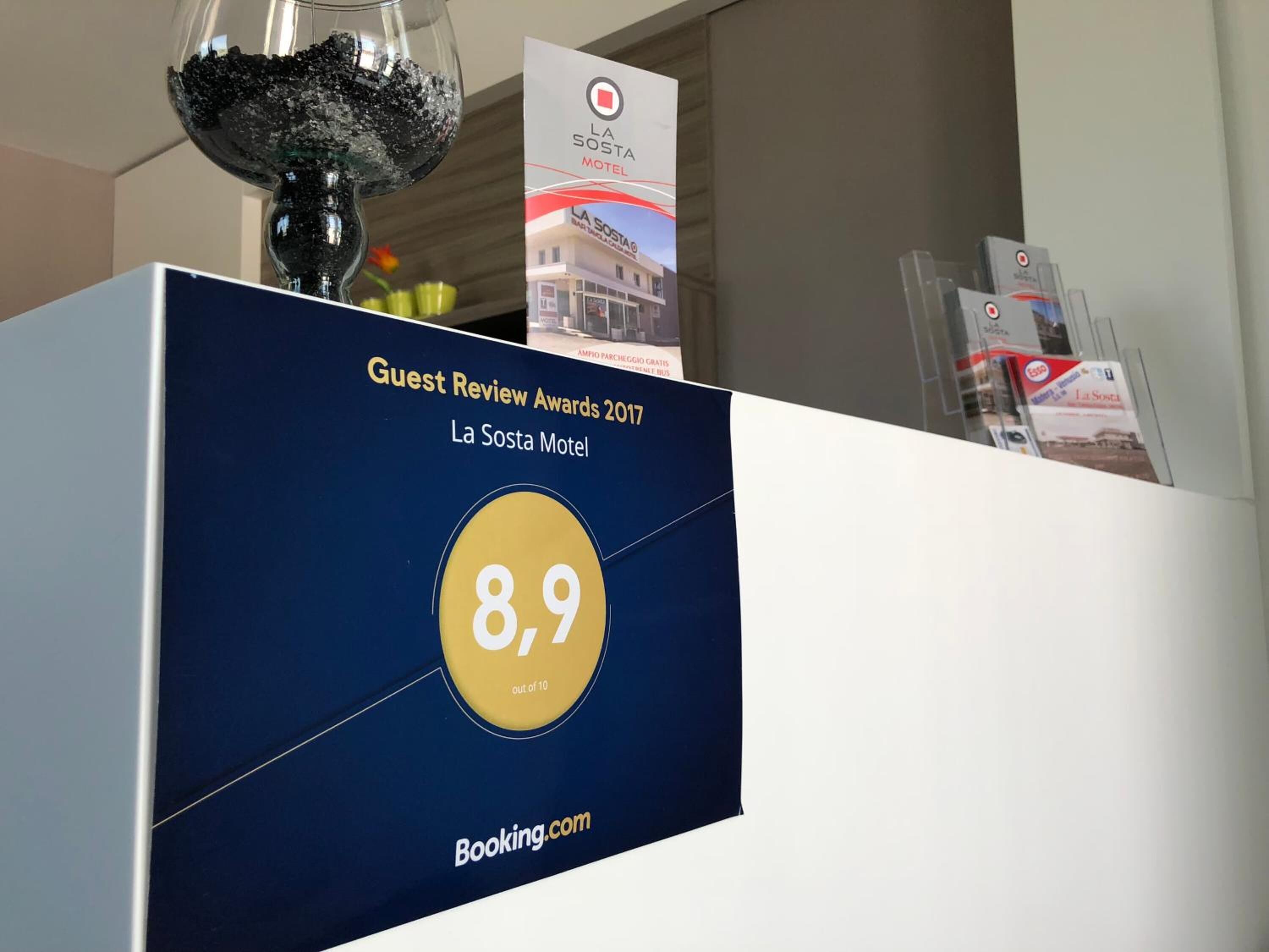 Un panel de exhibición con un premio por reseña de huéspedes para el motel La Sosta, con una calificación de 8.9 sobre 10.