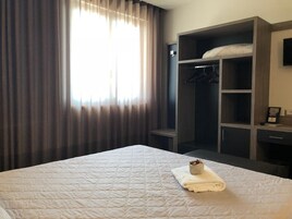Habitación de hotel con una cama grande, un armario y un televisor en la pared.