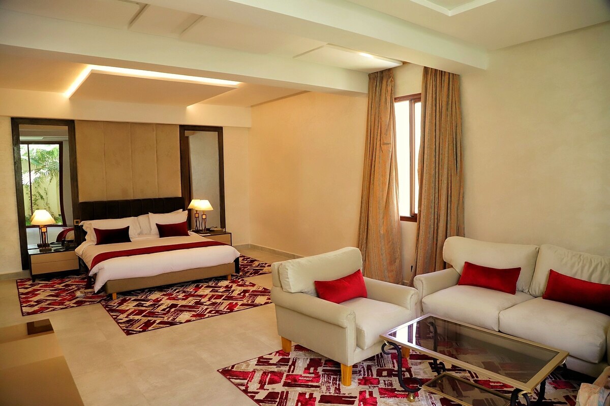 A hotel room with a bed, a sofa, a coffee table, and a large mirror.