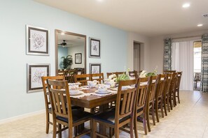 Un espace repas avec une longue table en bois, dressée pour six personnes, entourée de chaises en bois.