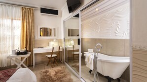 A modern bathroom with a freestanding bathtub, a vanity with a mirror, and a desk with a chair. - SelaMod Village guest House (Chaneng)