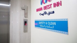 Placa de hotel com a inscrição 'NANA BEST INN' e 'SEGURANÇA E LIMPEZA', em inglês e em árabe.