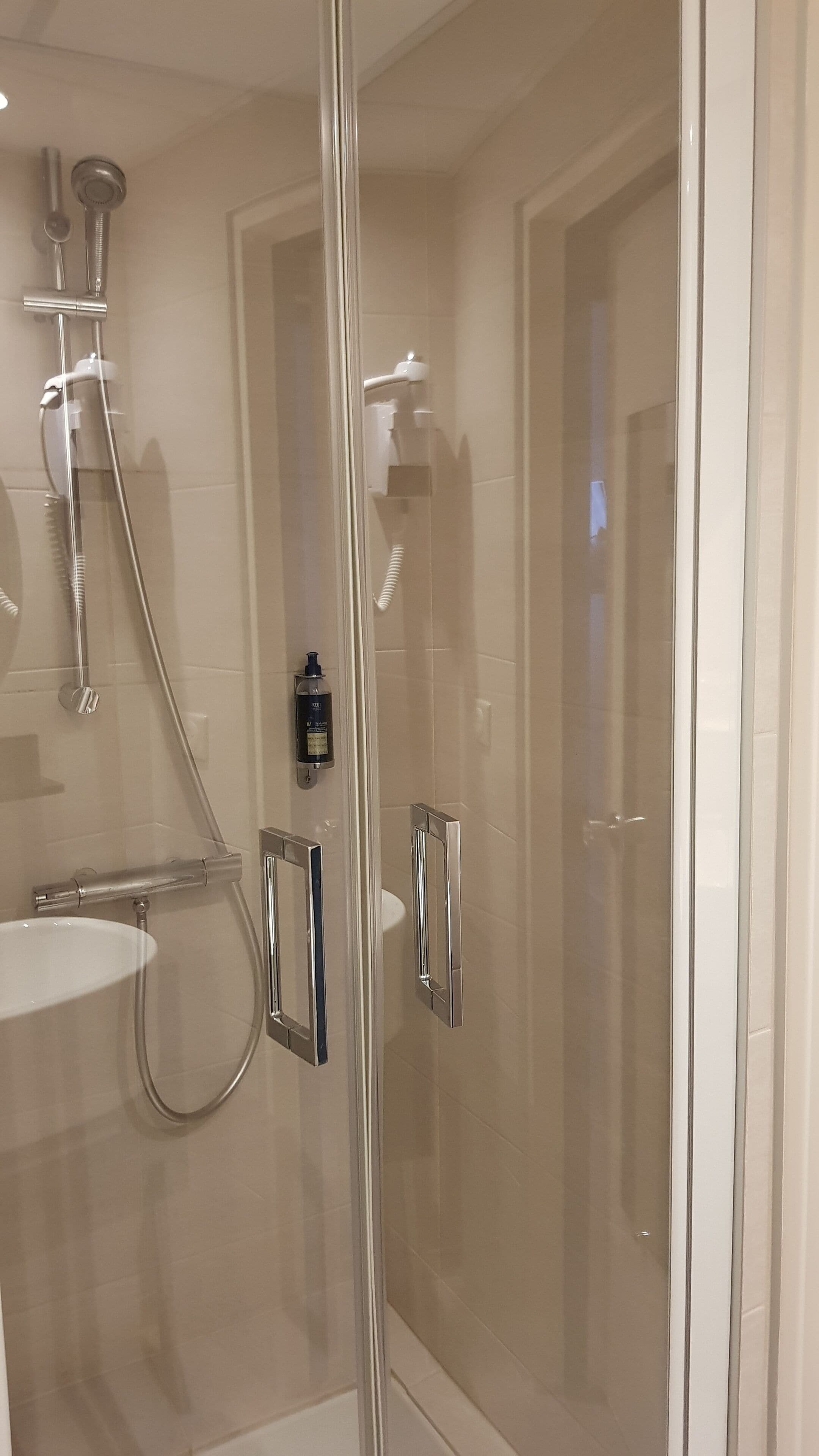 A modern bathroom with a glass-enclosed shower, a white sink, and chrome fixtures.