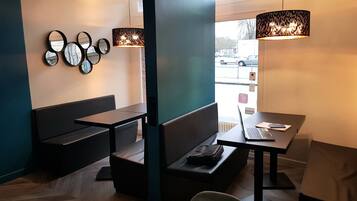 Un intérieur moderne avec un espace salon comprenant un banc et une table sur laquelle se trouve un ordinateur portable.