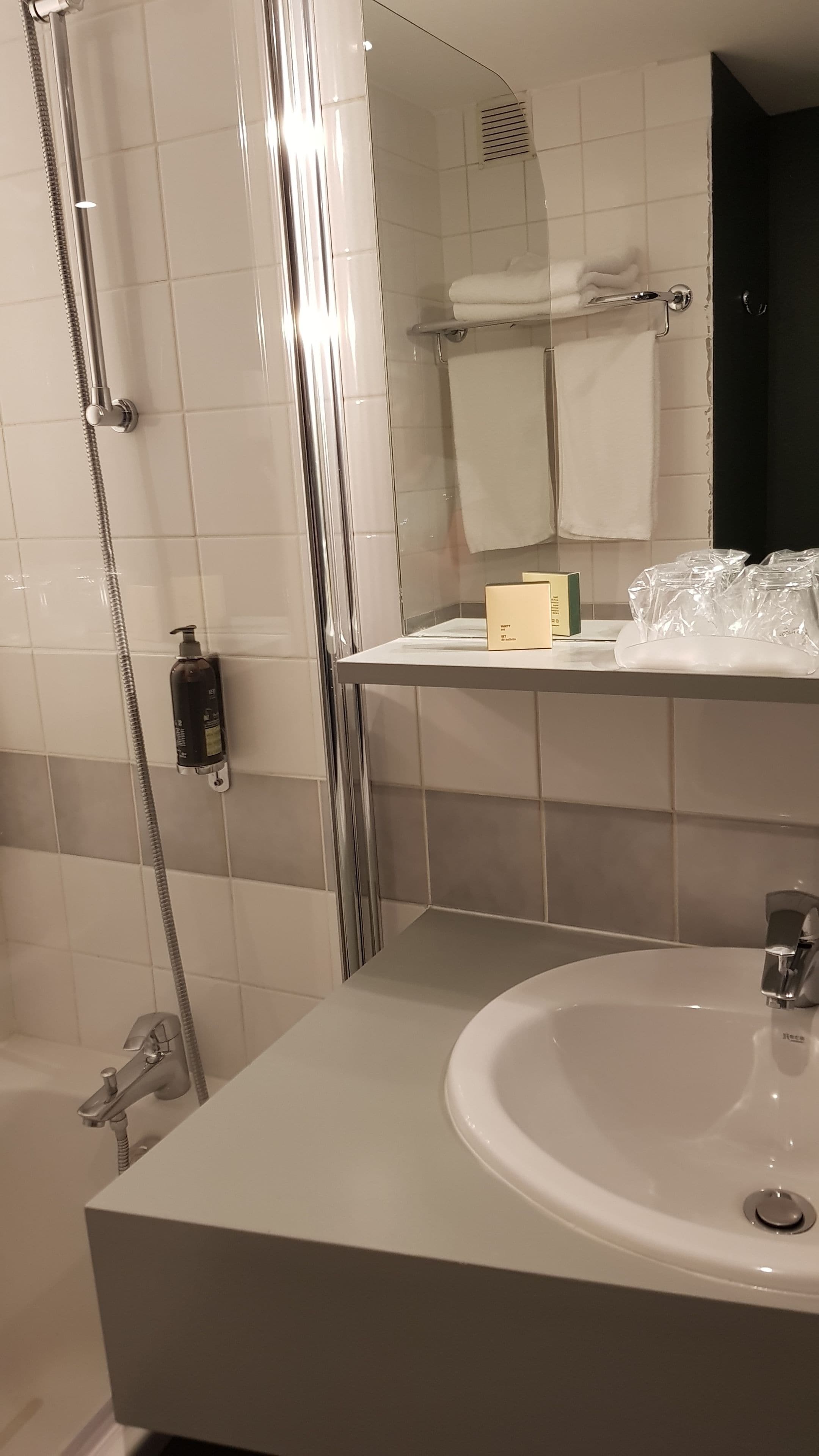 Un baño moderno con ducha envuelta en vidrio, un lavamanos blanco y un espejo sobre él.