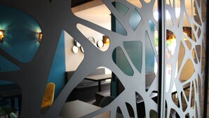 A modern interior with a decorative partition featuring geometric cutouts. - Hôtel de Champagne (Epernay)