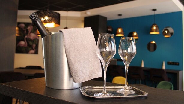 A bar area with a bottle of champagne, two glasses, and a tray on a table. - Hôtel de Champagne (Epernay)