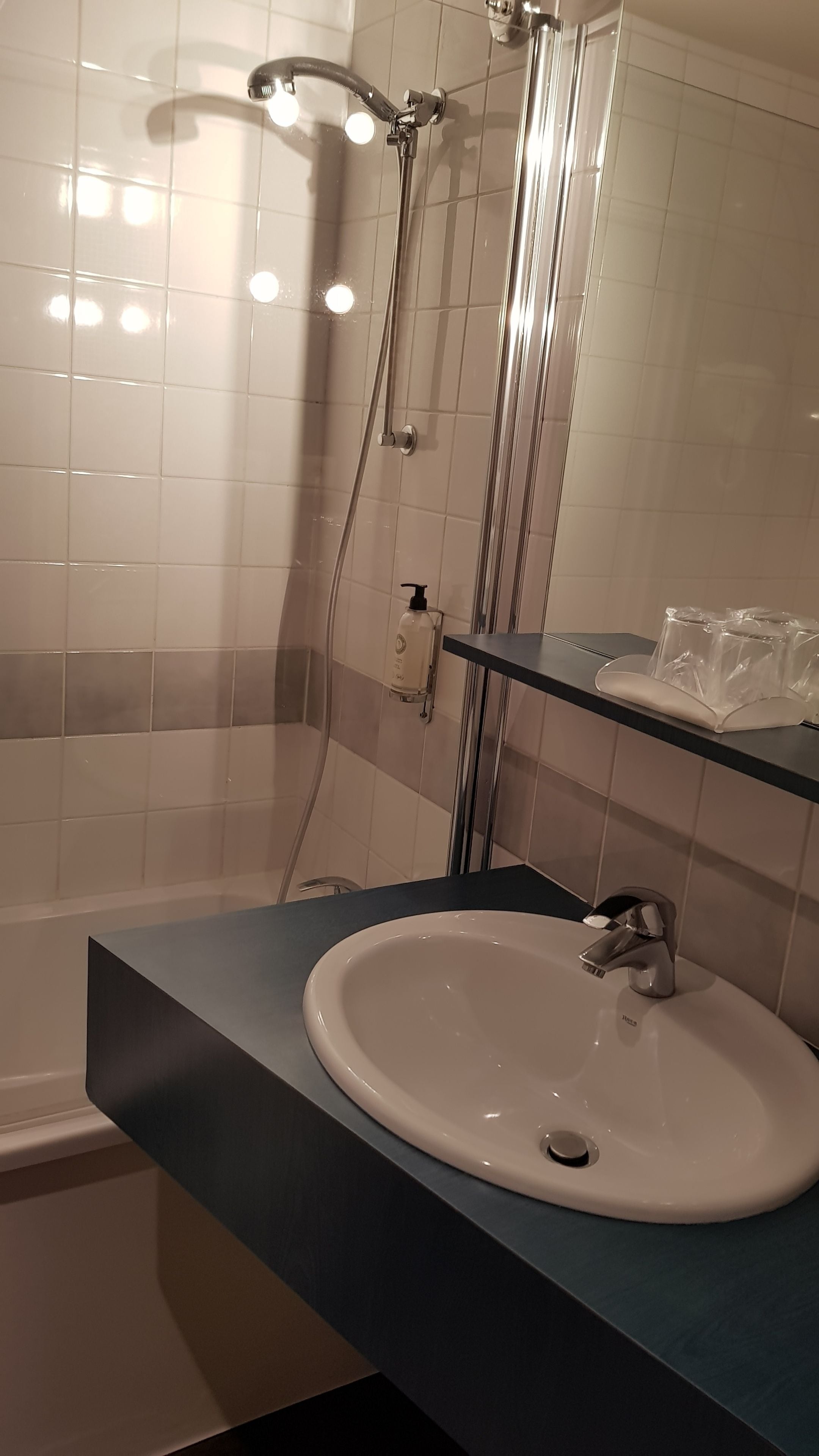 A modern bathroom with a white sink, a glass shower enclosure, and a mirror.