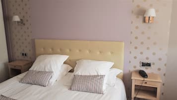 Habitación de hotel con una cama grande, dos mesitas de noche, una lámpara y un teléfono.