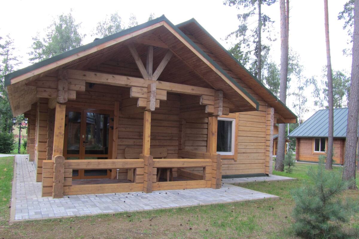 A wooden cabin with a porch, a small window, and a metal roof.