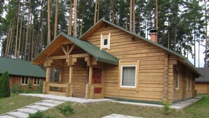 Een houten chalet met een veranda, een klein raam en een schoorsteen.