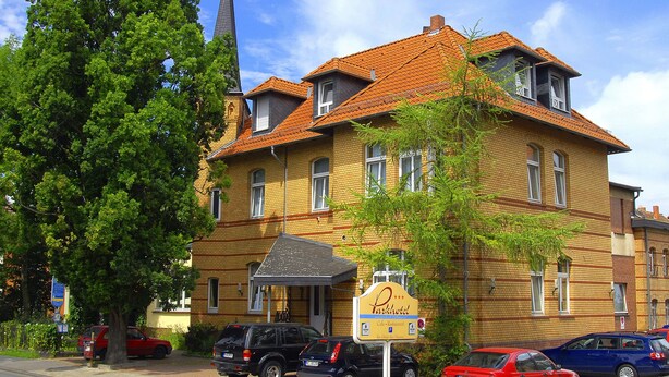 A yellow brick building with a sign for Parkhotel, featuring a cafe and restaurant. - Parkhotel (Nieheim)