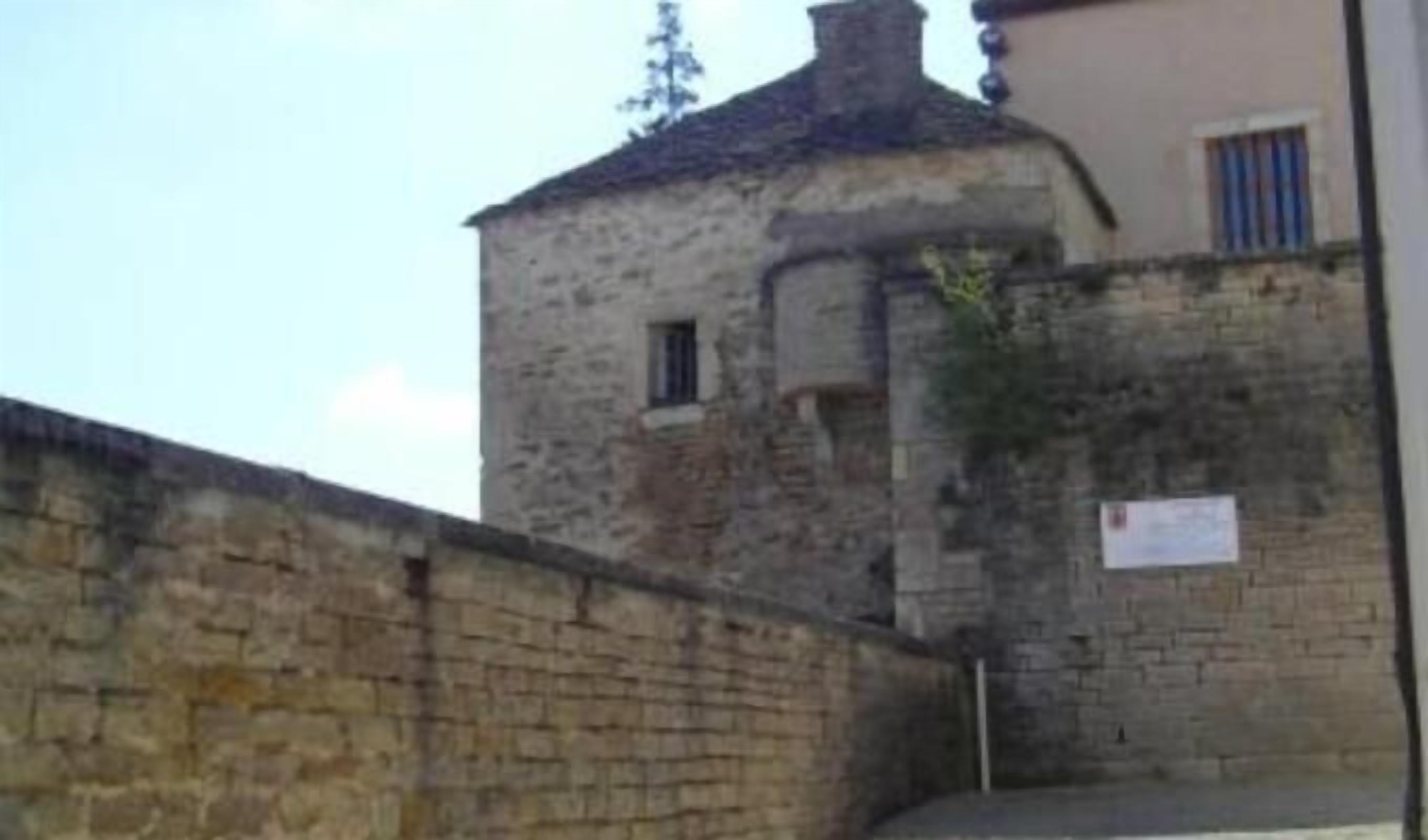 Un edificio in pietra con una piccola finestra e un portone, parte di una struttura più ampia.