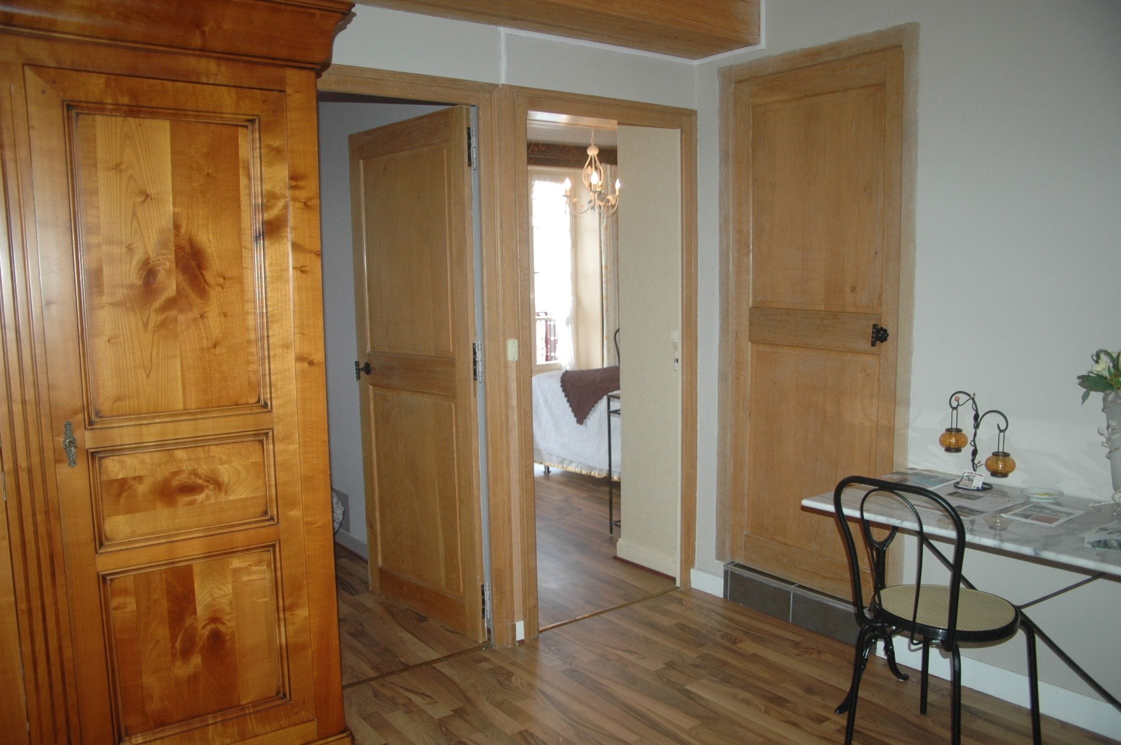 Una habitación con puertas de madera, una mesa de comedor con sillas y un candelabro.