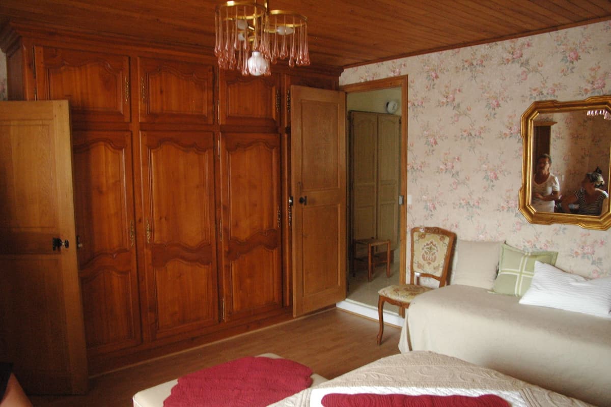 A bedroom with wooden wardrobes, a bed, a chair, and a mirror.