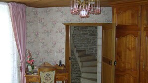 A room with a wooden desk, a chair, a vase with flowers, a staircase with stone steps, and wooden doors. - Le Puits Fortifie (Salives)