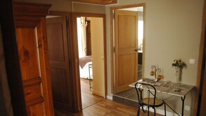 A room with wooden flooring, a dining table with chairs, and a wooden door. - Le Puits Fortifie (Salives)