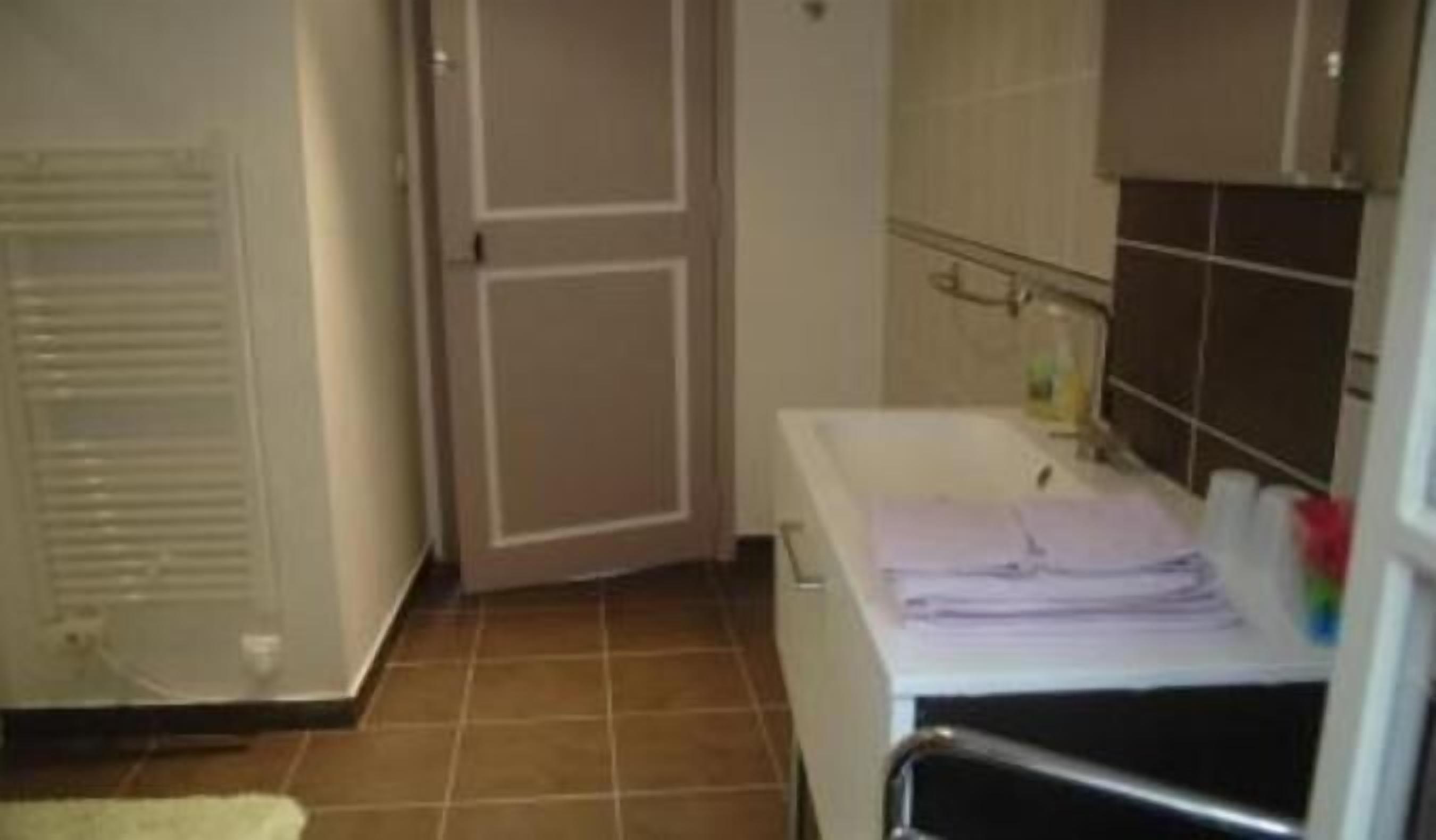 Un baño pequeño y limpio con una bañera blanca, un perchero para toallas y una puerta.