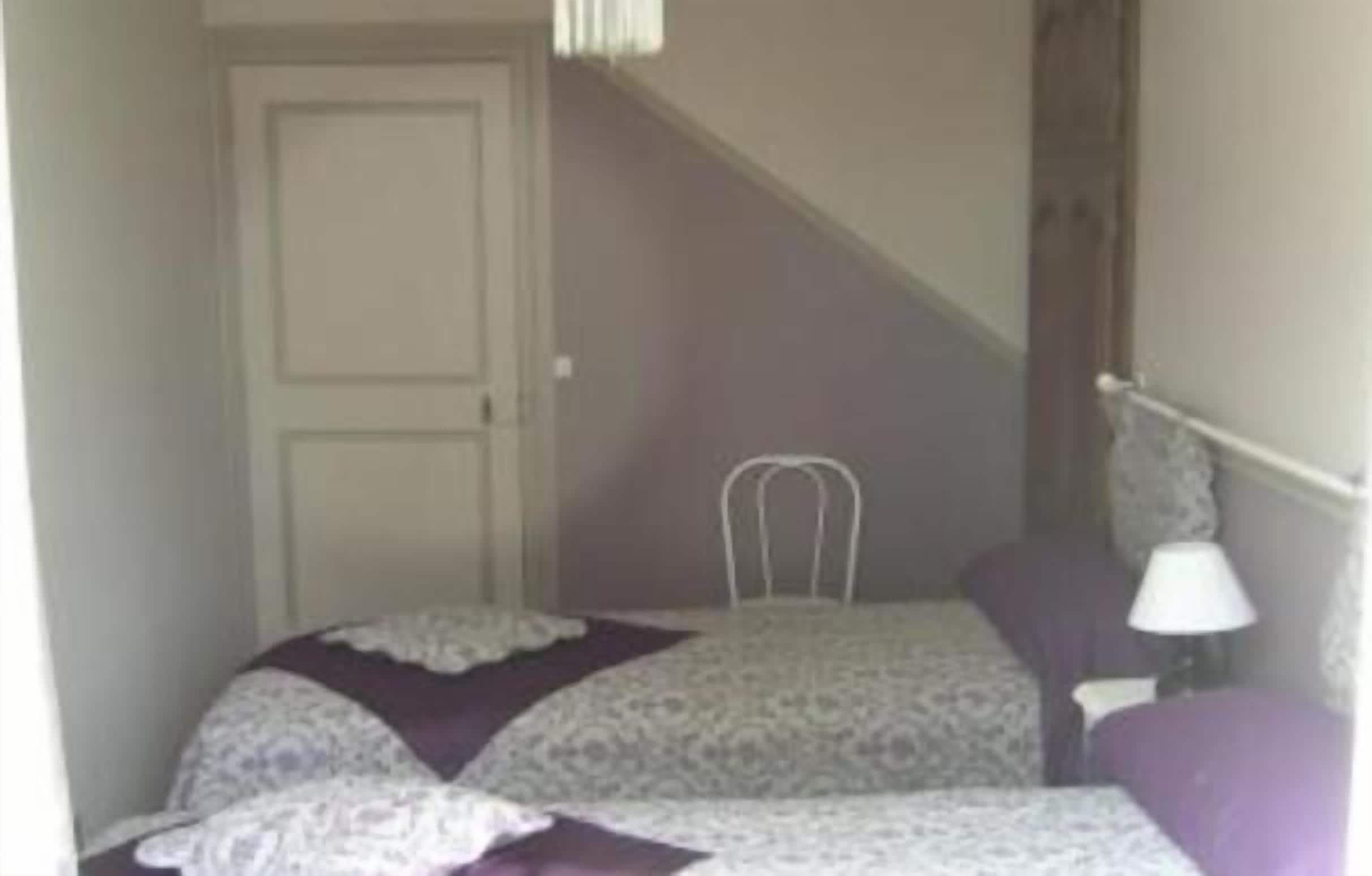 A bedroom with a bed, a chair, a lamp, and a door.