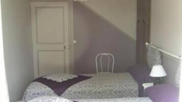 A bedroom with a bed, a chair, a lamp, and a door.