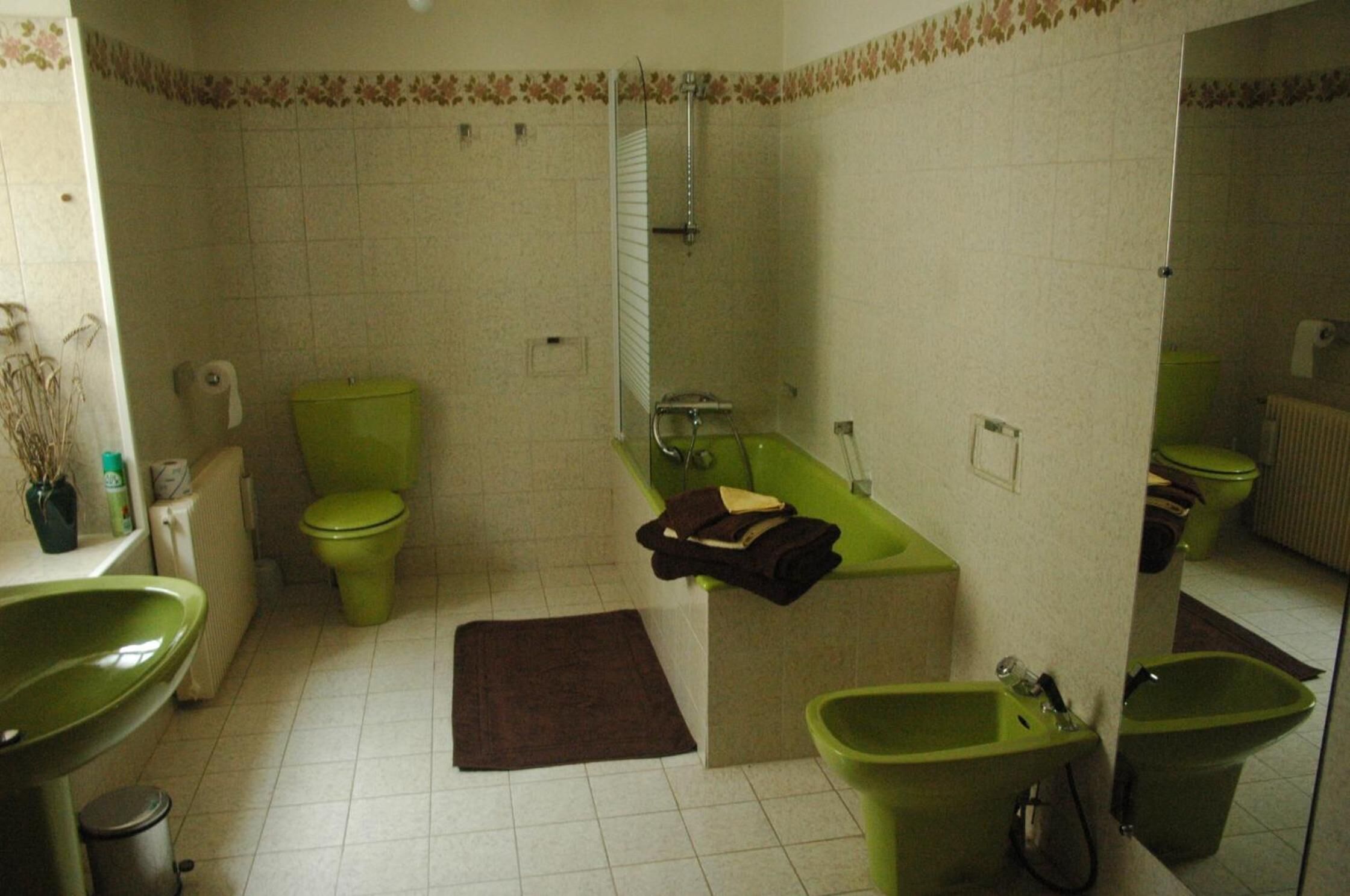 Et badeværelse med toilet, badekar og vask i grøn farve.
