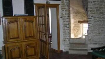 A room with a wooden cabinet, a stone wall, and a doorway leading to another room.