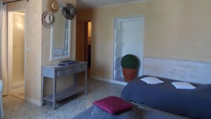 A bedroom with a bed, a vanity with a mirror, a small table, and a potted plant. - Clos Mazerolles (Cruzy)
