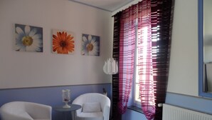 A room with two white armchairs, a small table with a glass top, and a colorful striped rug. - Clos Mazerolles (Cruzy)