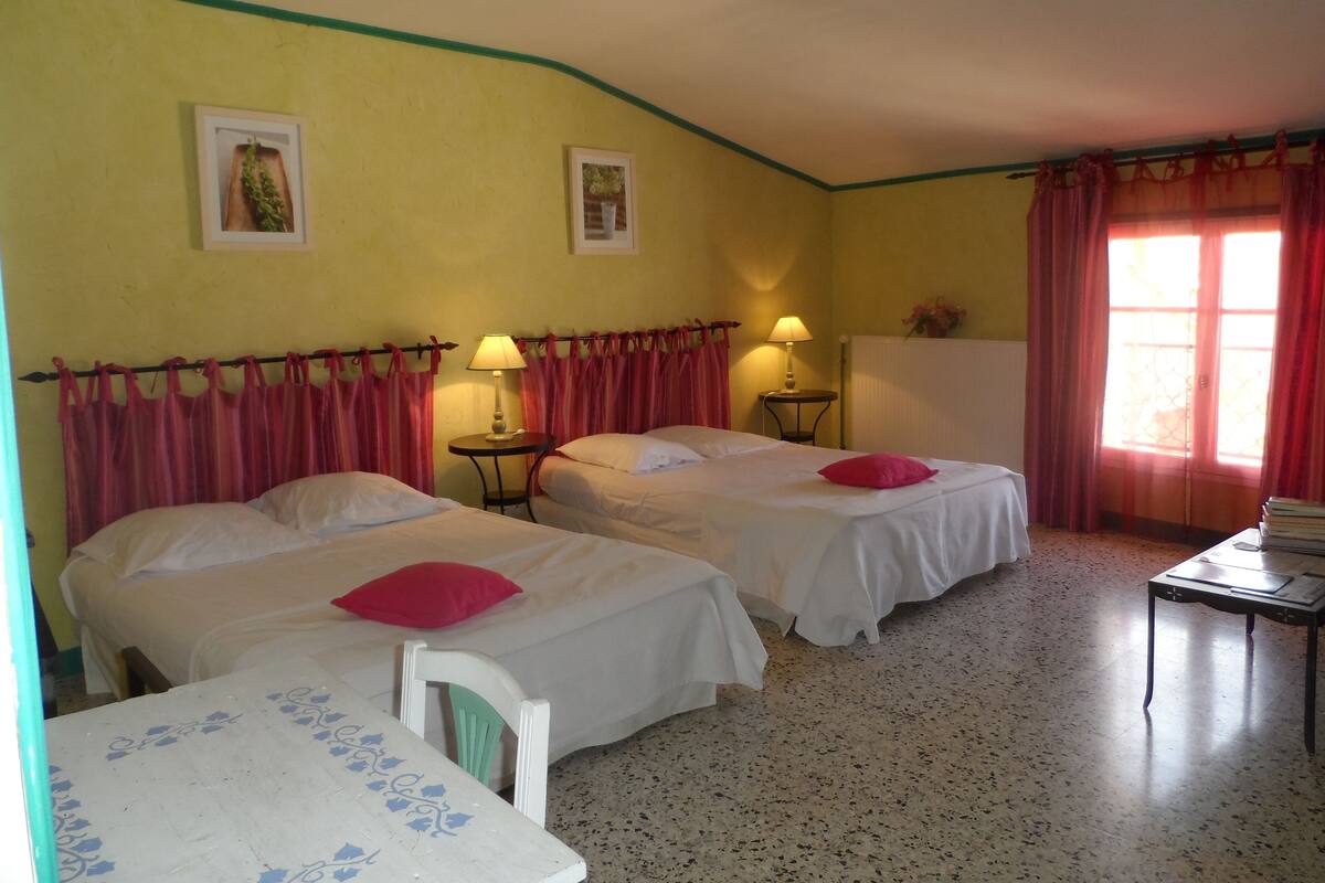 A room with two beds, a small table, and a window with curtains.