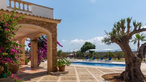 Ein Poolbereich mit Pergola, Kübelpflanzen und Liegestühlen.