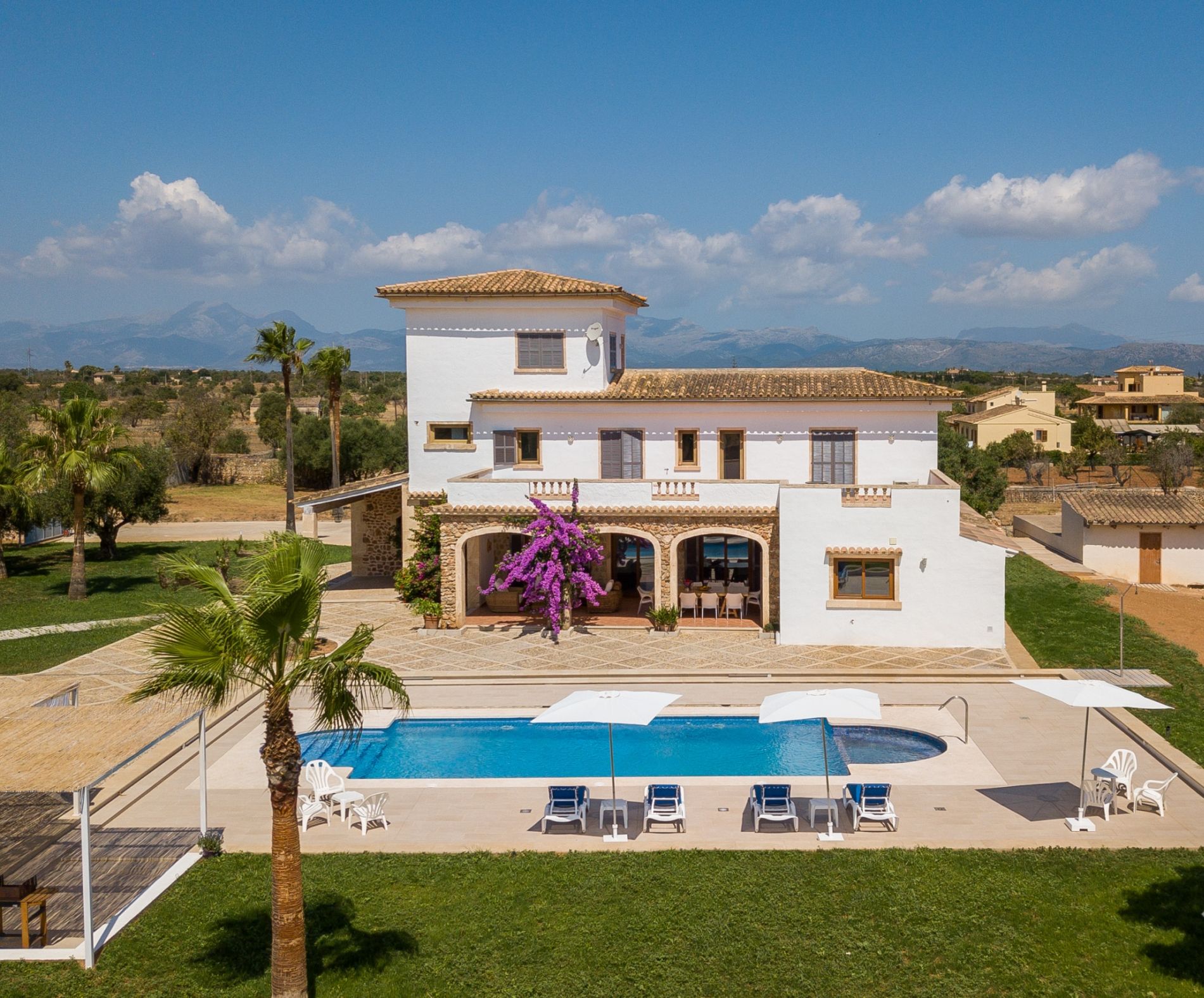 Une maison à deux étages avec une piscine, un espace salon extérieur et une vue sur les montagnes.
