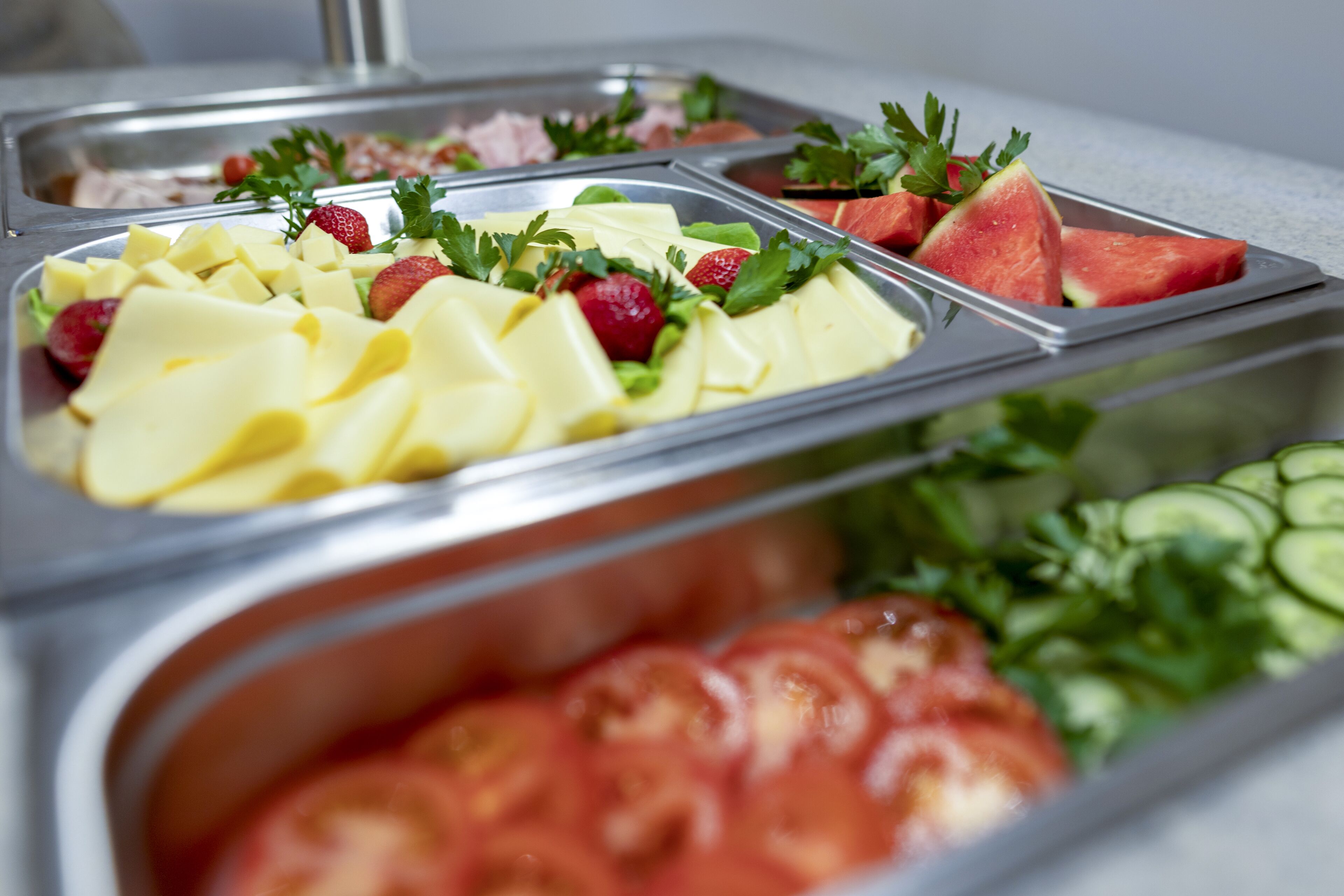 Un buffet proposant une variété d’aliments, notamment du fromage, des fraises, de la pastèque et des tomates.