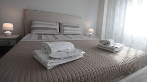 A neatly made bed with a quilted headboard, two pillows, and folded towels on the bed. - Alla Vista Del Barocco (Lecce)