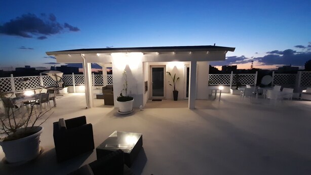 A rooftop patio with outdoor seating, potted plants, and a covered area with a door. - Alla Vista Del Barocco (Lecce)