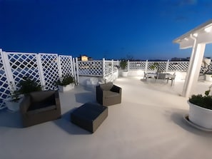 An outdoor patio area with white lattice fencing, potted plants, and outdoor furniture. - Alla Vista Del Barocco (Lecce)