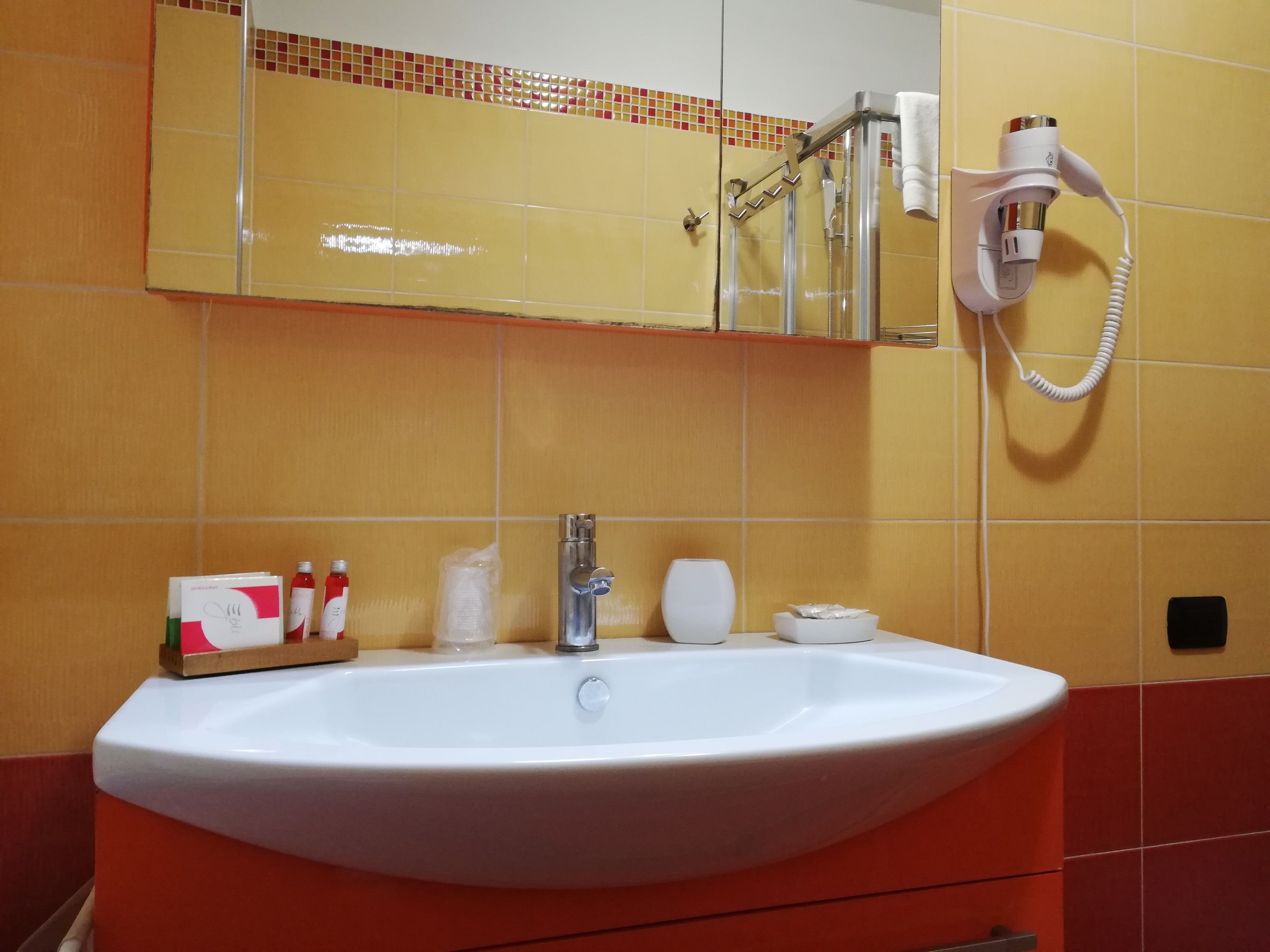 Un baño con un lavamanos blanco, un espejo y un perchero para toallas.