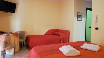 Una habitación de hotel con dos camas, un escritorio con una silla, un televisor y una puerta verde.