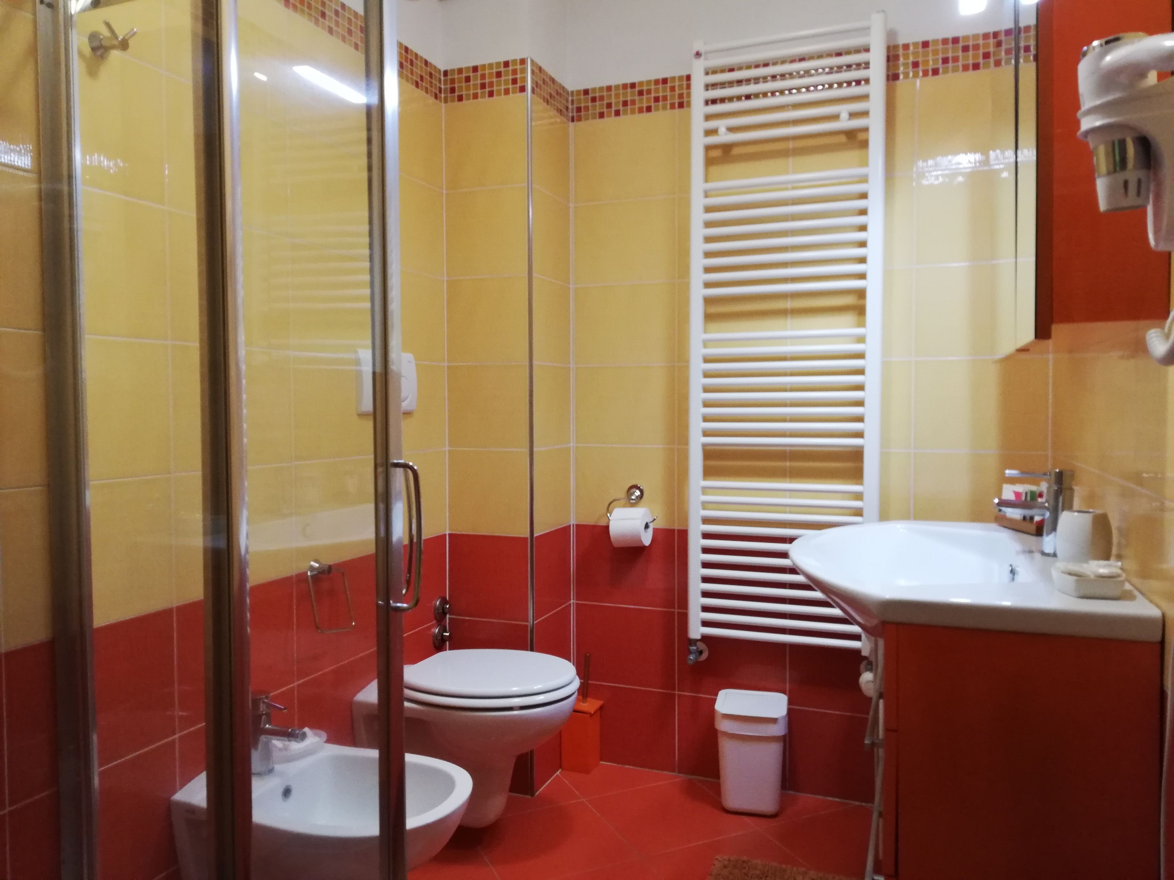 Un baño con ducha, dos inodoros, un lavabo y un perchero para toallas.