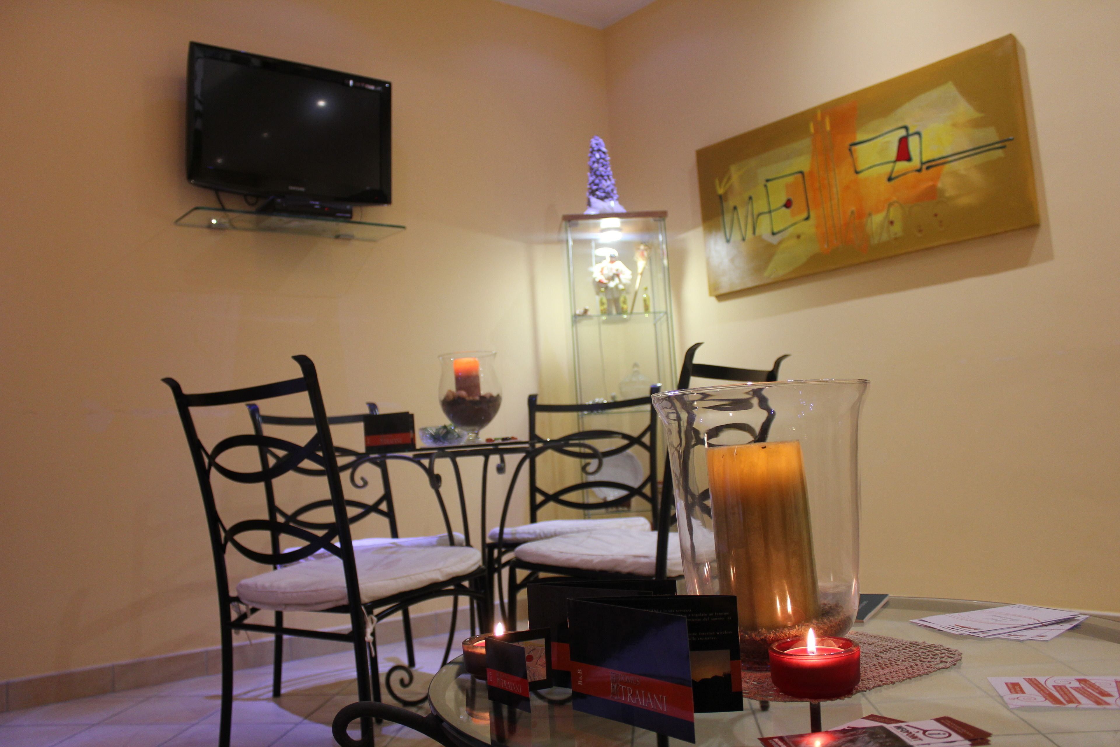 Un comedor con una mesa, sillas, una vela y un televisor montado en la pared.