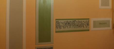 Una escalera con barandilla, un muro con arco y tres placas con obras de arte.