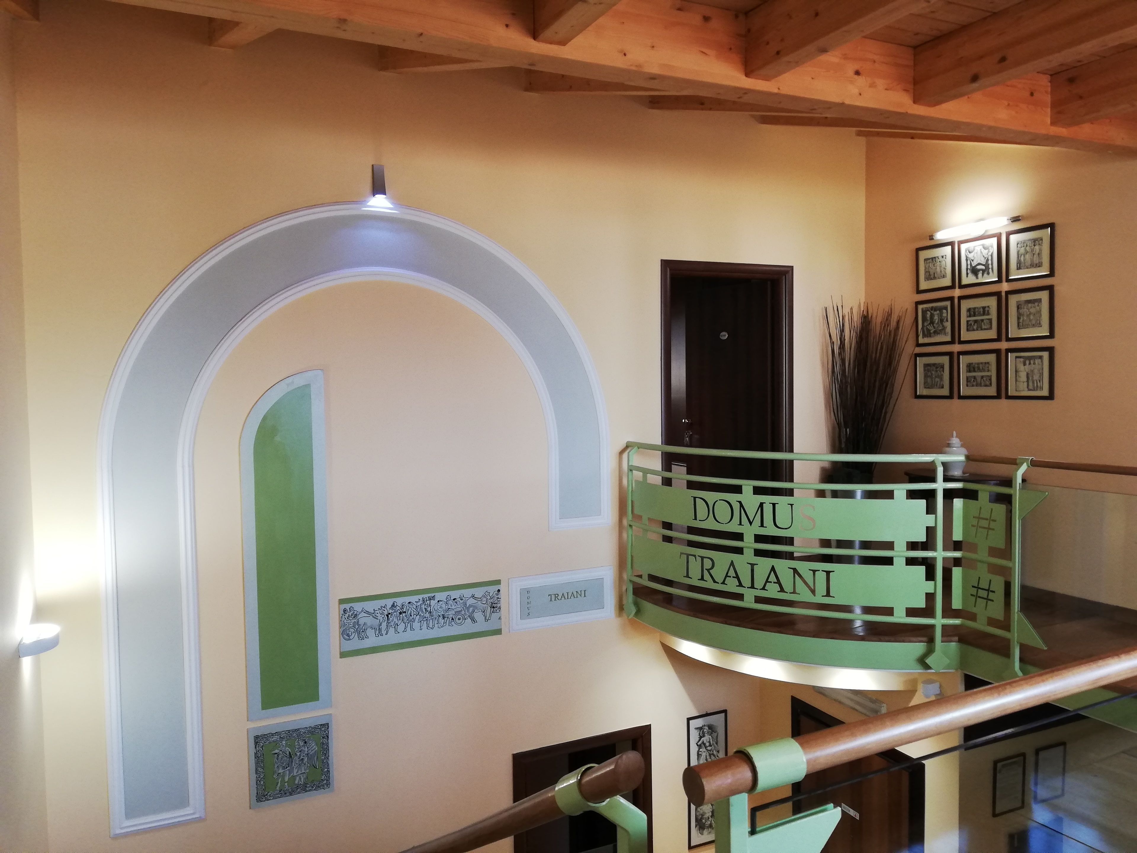 Uma escadaria com corrimão verde e uma placa que diz 'DOMUS TRAIANI'.