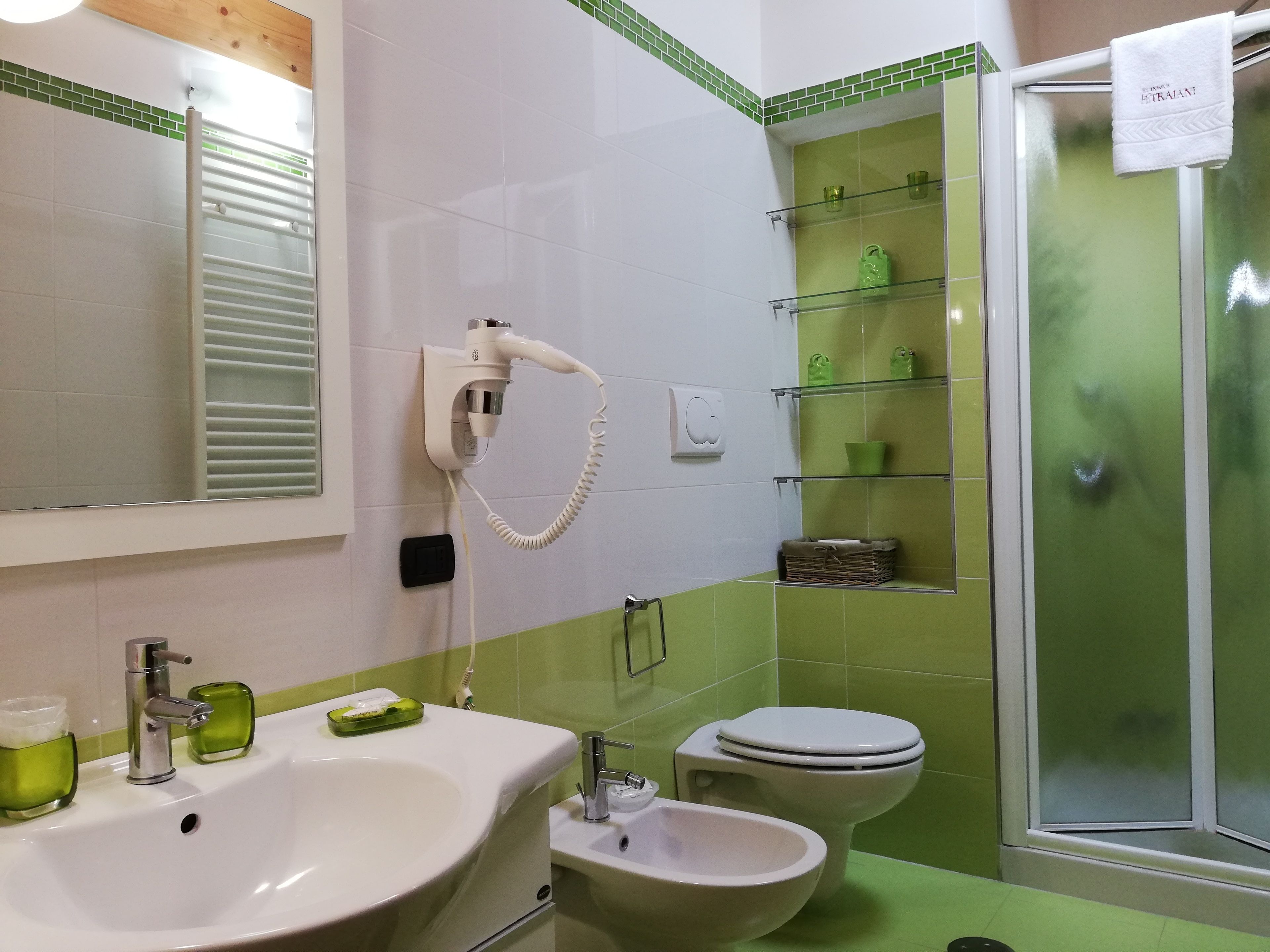 A bathroom with a sink, bidet, toilet, and a glass shower enclosure.